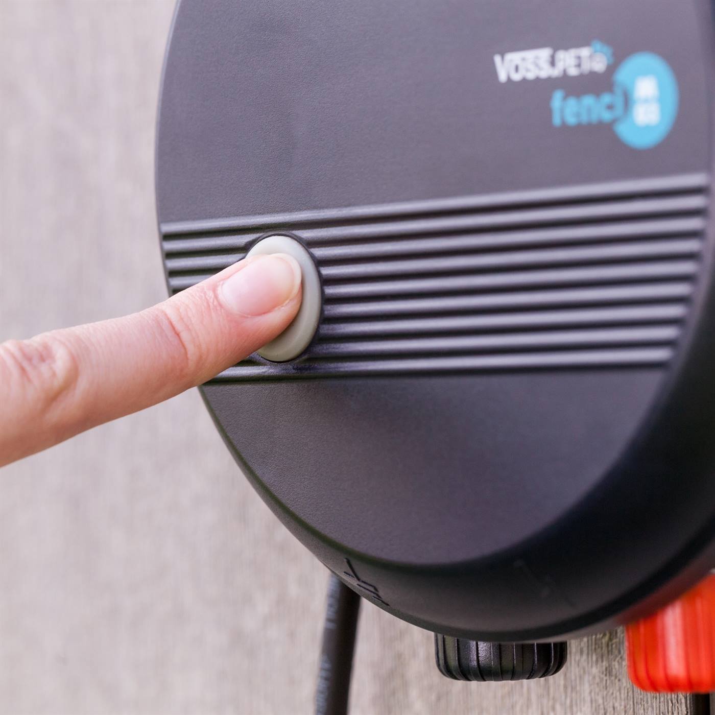 Eén vinger drukt op de aan/uit-schakelaar van het schrikdraadapparaat.